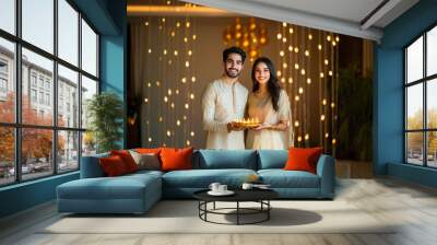 young indian couple holding oil lamp plate together on diwali Wall mural