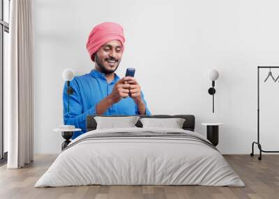 Young indian farmer using mobile phone over white background. Wall mural