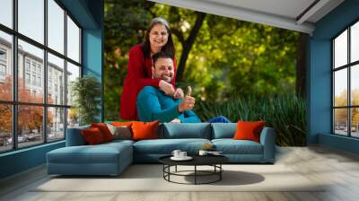 Young indian man showing thumps up with senior woman at park Wall mural