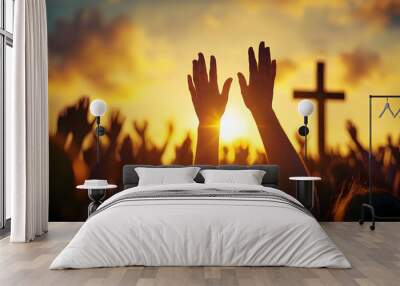 Hands raised in worship in front of a cross at sunset. Wall mural