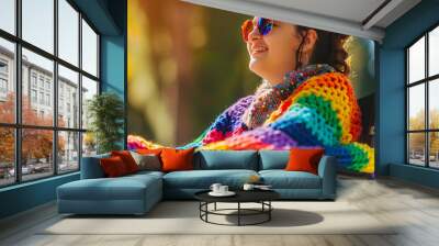 Happy disabled young girl in wheelchair wearing rainbow pride fashionable jumper cardigan outfit outdoors in nature. Candid young teenager with disability at LGBTQ  gay pride parade. Copy space Wall mural