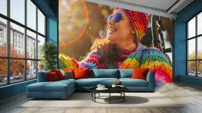 Happy disabled young girl in wheelchair wearing rainbow pride fashionable jumper cardigan outfit outdoors in nature. Candid young teenager with disability at LGBTQ  gay pride parade. Copy space Wall mural