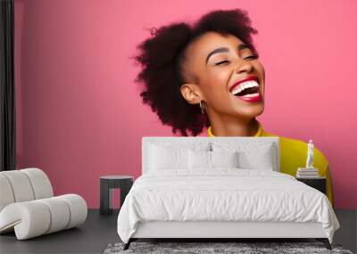 Happy optimistic African American woman in colorful pink clothes laughing isolated on yellow background Wall mural