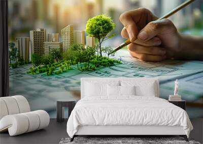 Person sketching a sustainable green city concept with eco friendly buildings and a tree on paper, representing urban planning and environmental conservation Wall mural