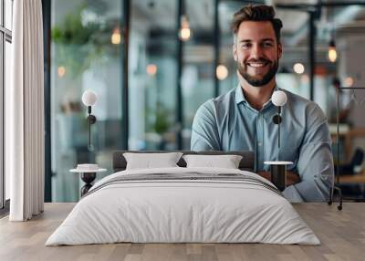 Portrait of cheerful businessman with arms folded standing in conference room. Happy young business man in shirt looking at camera. Portrait of a smiling businessman in modern office Wall mural