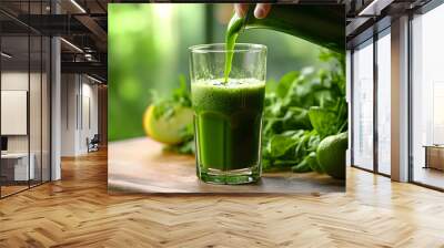 Pouring green juice into a glass. Wall mural