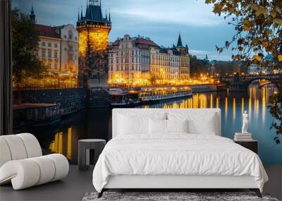 Sitkov Water Tower and the Vltava Embankment in Prague, Czechia. The historic water tower stands tall against a backdrop of brightly lit buildings lining the riverbank. Prague dusk picturesque Wall mural