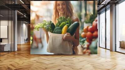 Young lady holding fruits and vegetables into reusable cotton produce bag on food market, sustainable lifestyle and eco shopping concept Wall mural