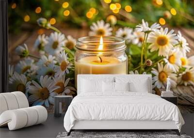 Candle in jar with lit flame among fresh daisies on wooden surface Wall mural