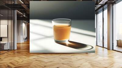 A glass of tea sits on a plain white table, illuminated by soft natural light from a nearby window.  Wall mural