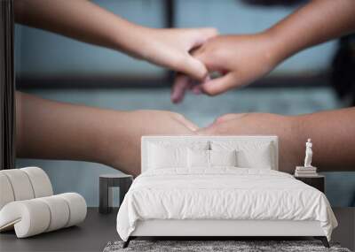 Two children's hands holding hands in close-up, natural light with blurred background. Wall mural