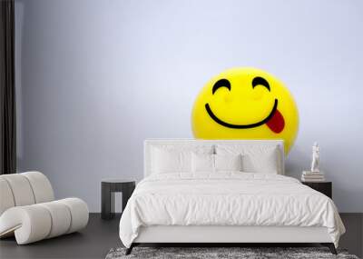 Yellow smiley showing tongue on a white background Wall mural