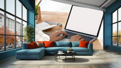 Close-up image of beautiful business woman sitting at the wooden work desk and typing on the white blank screen laptop keyboard. Wall mural