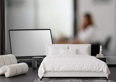 Computer laptop with white blank screen putting on modern working desk with blurred background. Wall mural