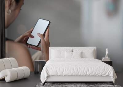 Cropped image of a woman's hands is using a mobile phone with a white blank screen. Wall mural