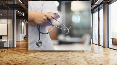 Cropped image of doctor holding a stethoscope while standing in hospital with blurred background Wall mural