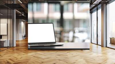 Photo of computer laptop with white blank screen putting on the modern working table with blurred comfortable office as background. Void screen for advertise concept. Wall mural