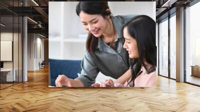 Smiling young female employee helping her colleague working in office. Wall mural