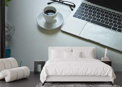 The top view image of the white working desk is surrounding by a coffee cup and office equipment. Wall mural