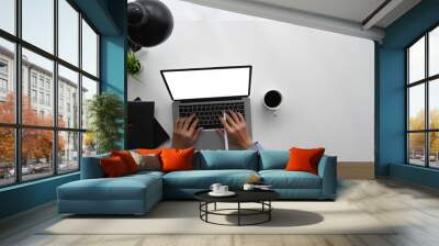 Top view image of businessman hand typing on white blank screen computer laptop at white working desk with office equipment. Wall mural