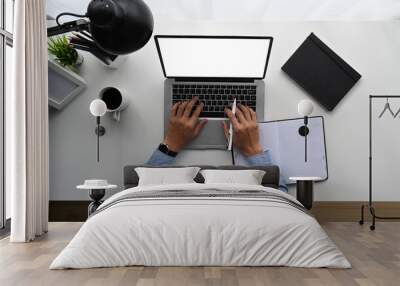 Top view of man is working on laptop while sitting at the white wooden desk. Wall mural