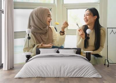 Two happy multiracial girls enjoying cake and drinking coffee in a coffee shop Wall mural