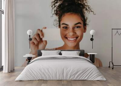 A photo of an attractive woman smiling and holding up her white business card against a solid white background, in the style of an Instagram post Wall mural