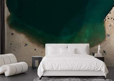 High angle shot of people on sandy beach by large green tranquil seawater Wall mural