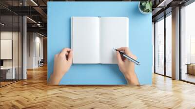 Person opening a book with blank pages, ready to write a new story Wall mural