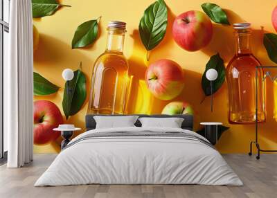 Apple cider vinegar in glass bottles with fresh apples around on yellow background. Wall mural