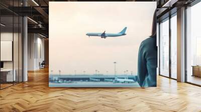 A traveler gazes out the airport window, watching a plane take off against a breathtaking sunset, capturing the essence of adventure. Wall mural