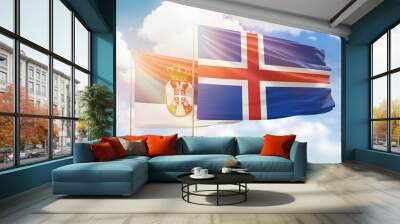 Sunny blue sky and flags of iceland and serbia Wall mural