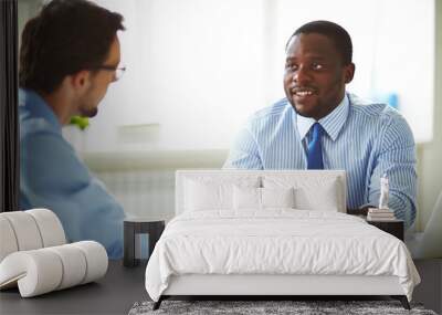 Afro-American bearded HR manager sitting at office desk while conducting interview with male applicant for position Wall mural