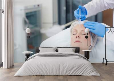 Aging female having anti-wrinkle injection in her forehead Wall mural