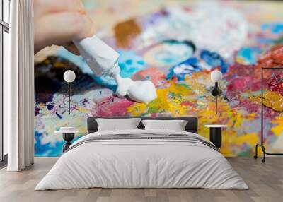 Artist or painter putting white gouache or paint on palette to mix it with other colors before painting Wall mural