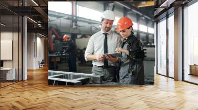 Asian metalworking specialist discussing technical sketch with engineer while they using engineering app on tablet Wall mural