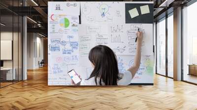 Back view of female coach with smartphone pointing at financial information Wall mural