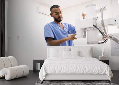 Bearded young mixed-race man in blue uniform using new medical equipment Wall mural