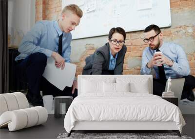 Businesswoman pointing at financial document with two men near by Wall mural