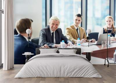 Cheerful excited senior businessman listening to colleagues at meeting, they planning business development together and sharing strategies Wall mural