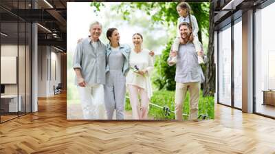 Cheerful family in casualwear walking down road in natural environment during chill Wall mural