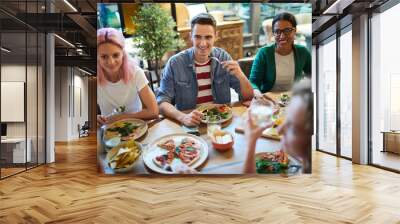 Cheerful intercultural young people gathered by cafe or restaurant for meal and talk Wall mural