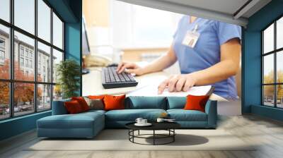 Close-up of unrecognizable nurse sitting at desk and using computer while analyzing medical notes Wall mural