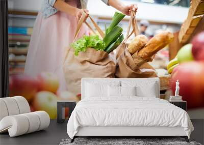 Close-up of unrecognizable woman in skirt standing in food organic store and picking heavy shopping bags full of products Wall mural