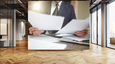 Closeup portrait of unrecognizable successful businessman wearing black formal suit reading contract documents at desk with laptop, busy with paperwork 
 Wall mural