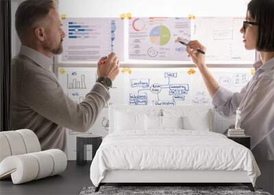 Contemporary economists standing by whiteboard and pointing at financial papers Wall mural