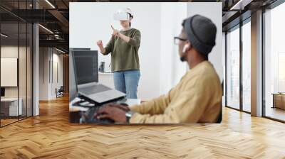 Contemporary young businesswoman in vr headset making virtual presentation in front of male colleague decoding data Wall mural