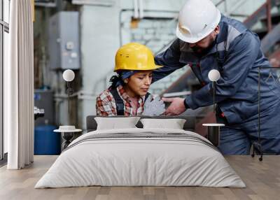 foreman in hardhat and workwear standing by female engineer with contusion touching her shoulder aga Wall mural