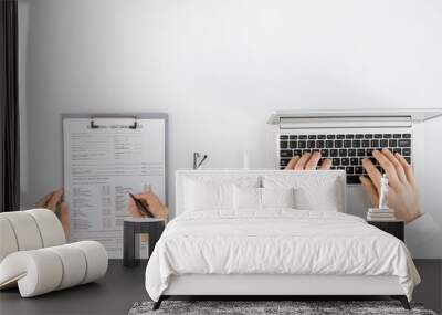 Hands of nurse with pen filling in medical history form next to male colleague Wall mural