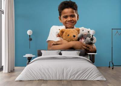 Happy little boy with two soft toys and teddybear smiling at you while playing Wall mural